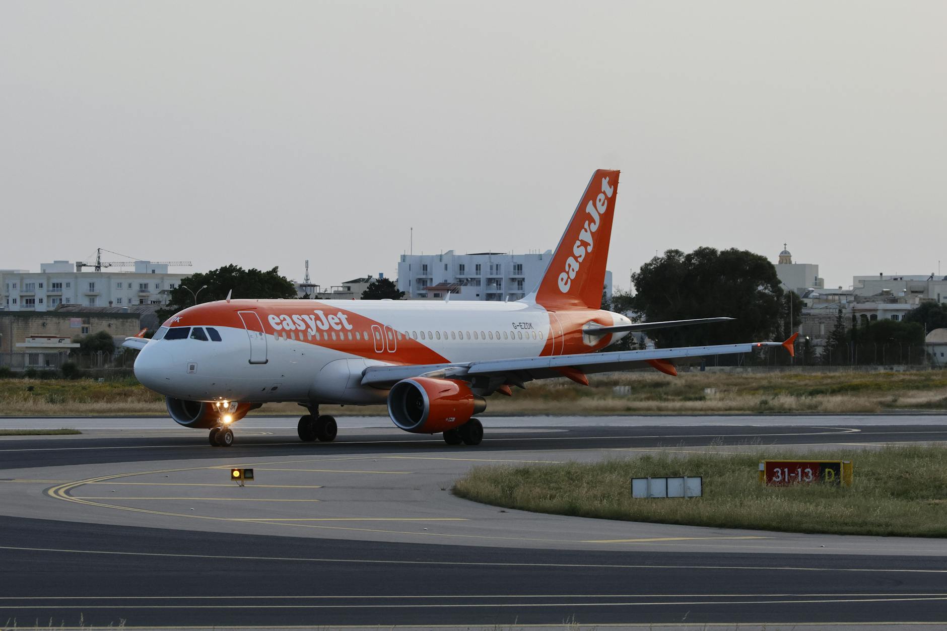 An easyJet plane prepares for takeoff on a sunny day at the airport.